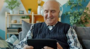 Persona mayor sonríe a la pantalla mejorando su bienestar emocional con inteligencia artificial Amy